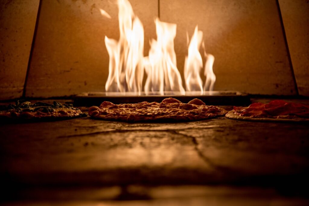A picture of a wood-fired oven with pizzas cooking inside it